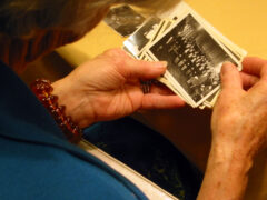 A reunion visitor looks through a handful of old photographs of the Auseklis camp high school.